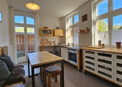 Gemütliche Küche mit großen Fenstern und natürlichem Licht, vollausgestattete Küche mit modernen Geräten, Holzdetails und Blick ins Grüne – perfekt für urgemütliche Mahlzeiten und entspanntes Kochen.