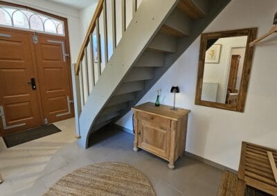 Eingangstür mit Holzdekor und Treppe, stilvoller Flur im Landhausstil, robustes Holzmobiliar, praktische Garderobe, freundlicher Empfangsbereich, hochwertige Holzelemente, idyllisches Ambiente, natürliche Materialien, behagliche Atmosphäre, Hausflur mit authentischem Flair.